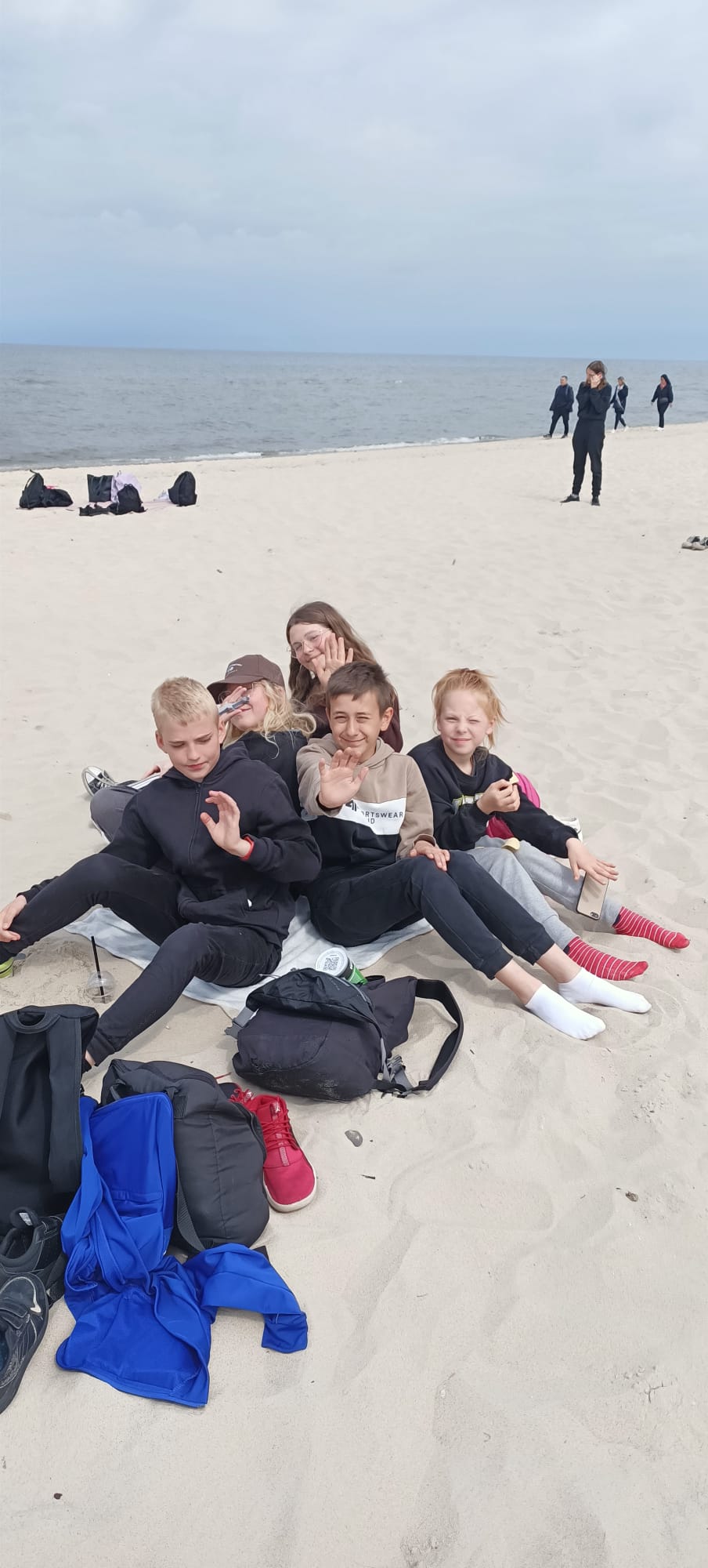 Grupa uczniów siedzi na plaży