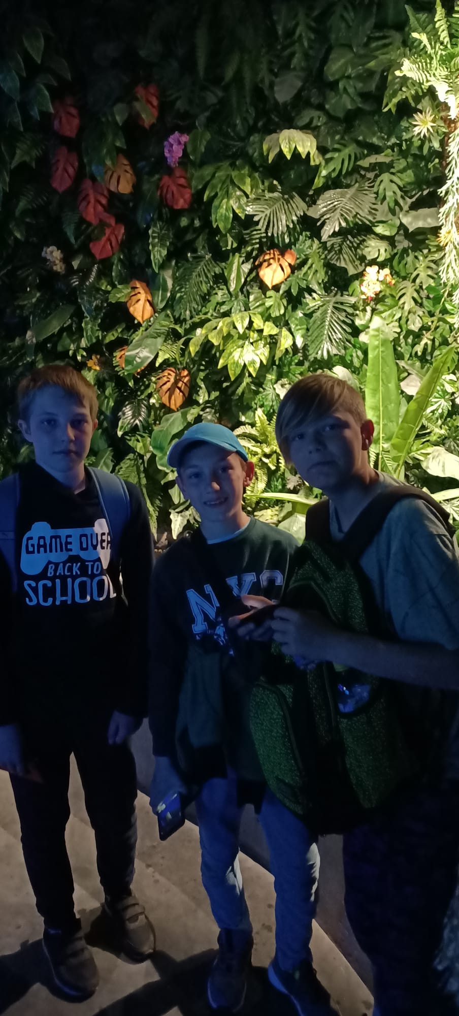 Trzech chłopców stoi na tle ściany pnących roślin