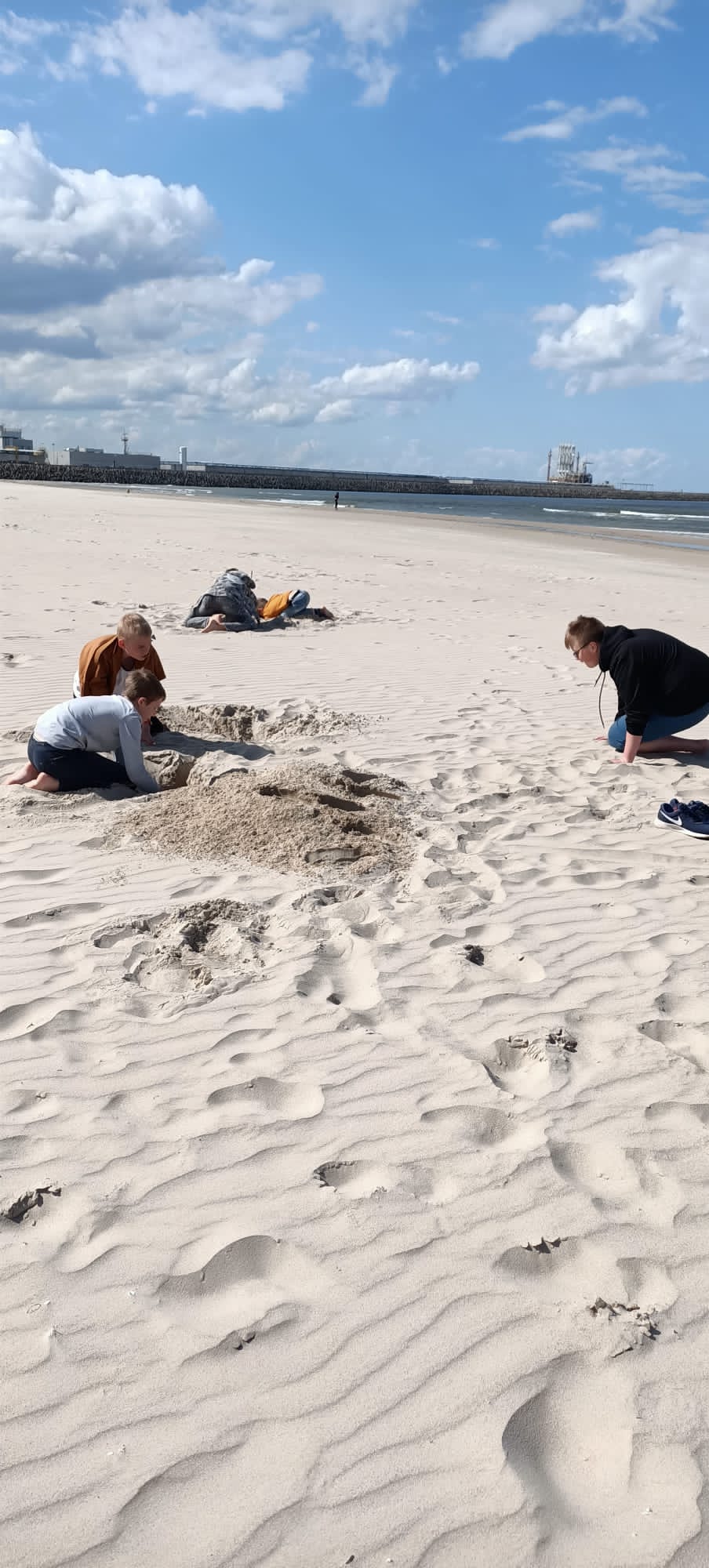 Grupa uczniów bawi się w piasku na plaży