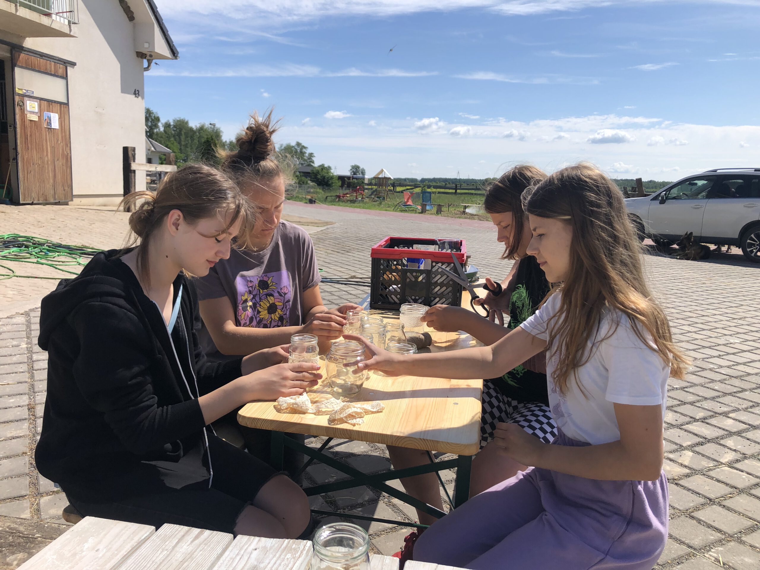 Cztery dziewczyny siedzą przy stoliku przygotowując dekorację na piknik ósmoklasisty