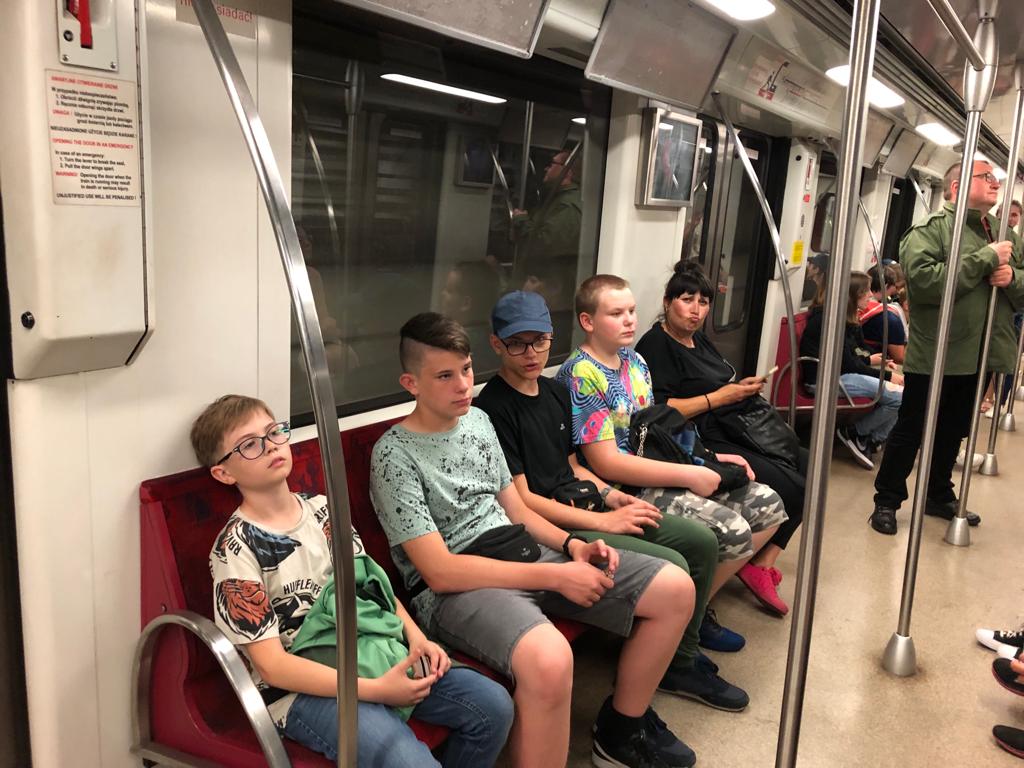 Czterch chłopców i nauczycielka siedzi w wagonie metra