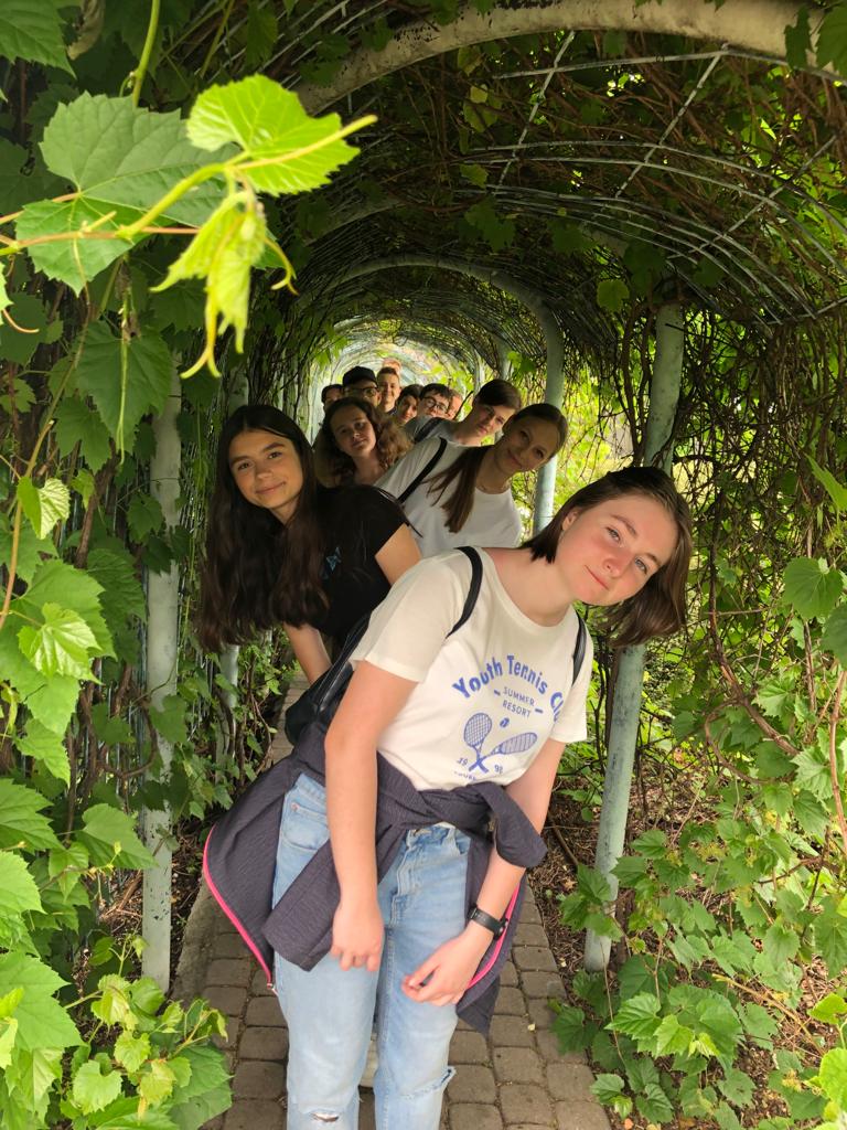 Grupa dziewcząt pozuje do zdjęcia w tunelu roślinnym