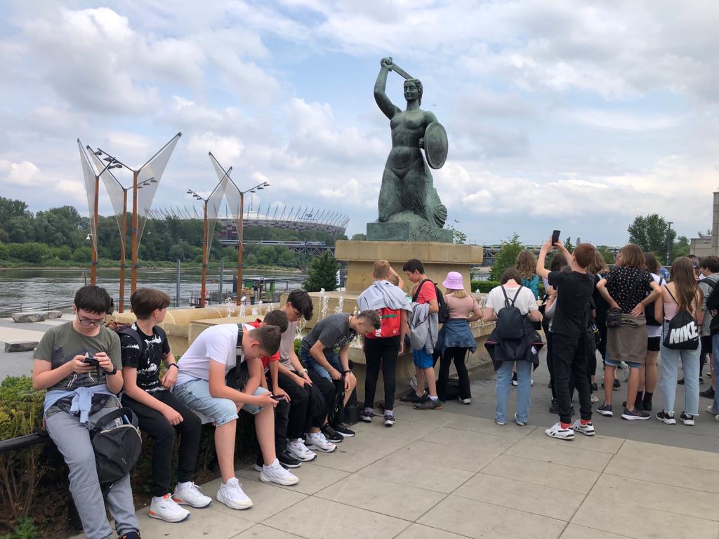 Grupa uczniów pod pomnikiem Syrenki nad Wisłą