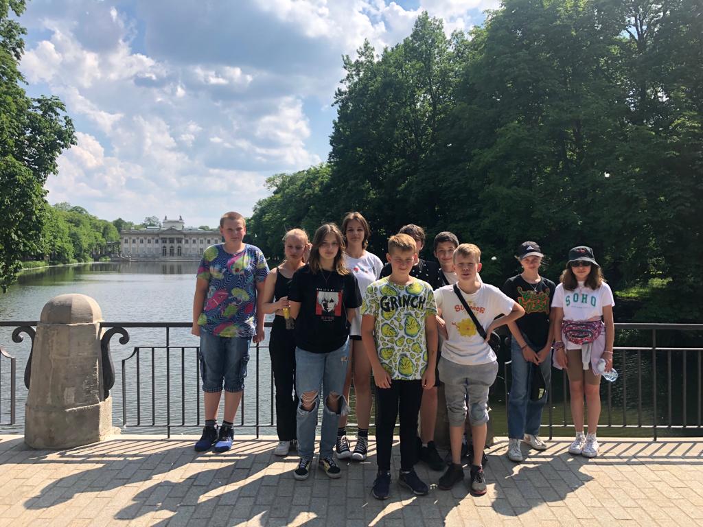 Uczniowie klasy 7a pozują do zdjęcia nad wodą w Łazienkach warszawskich