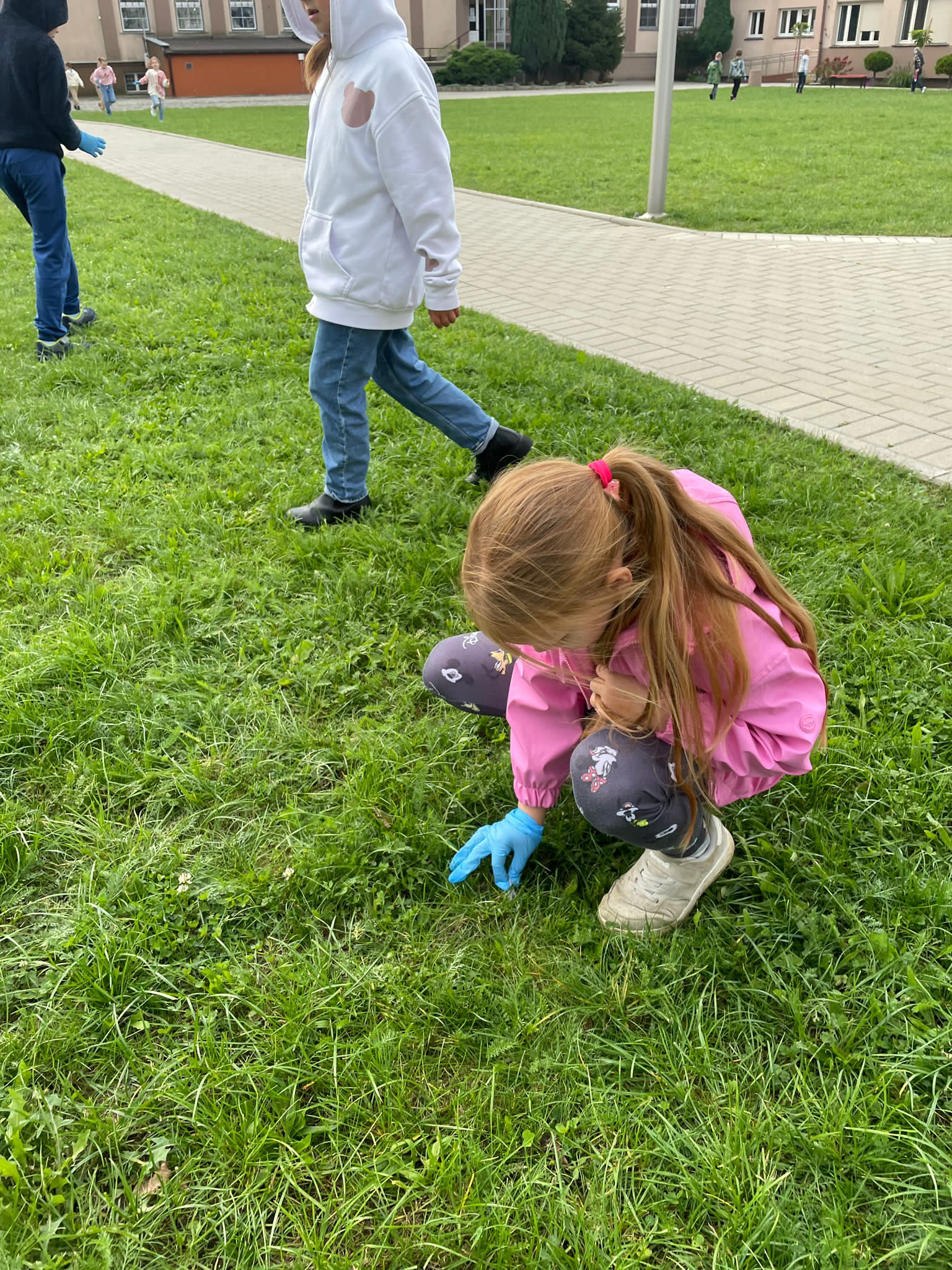Dziewczynka podnosi papierek z trawnika