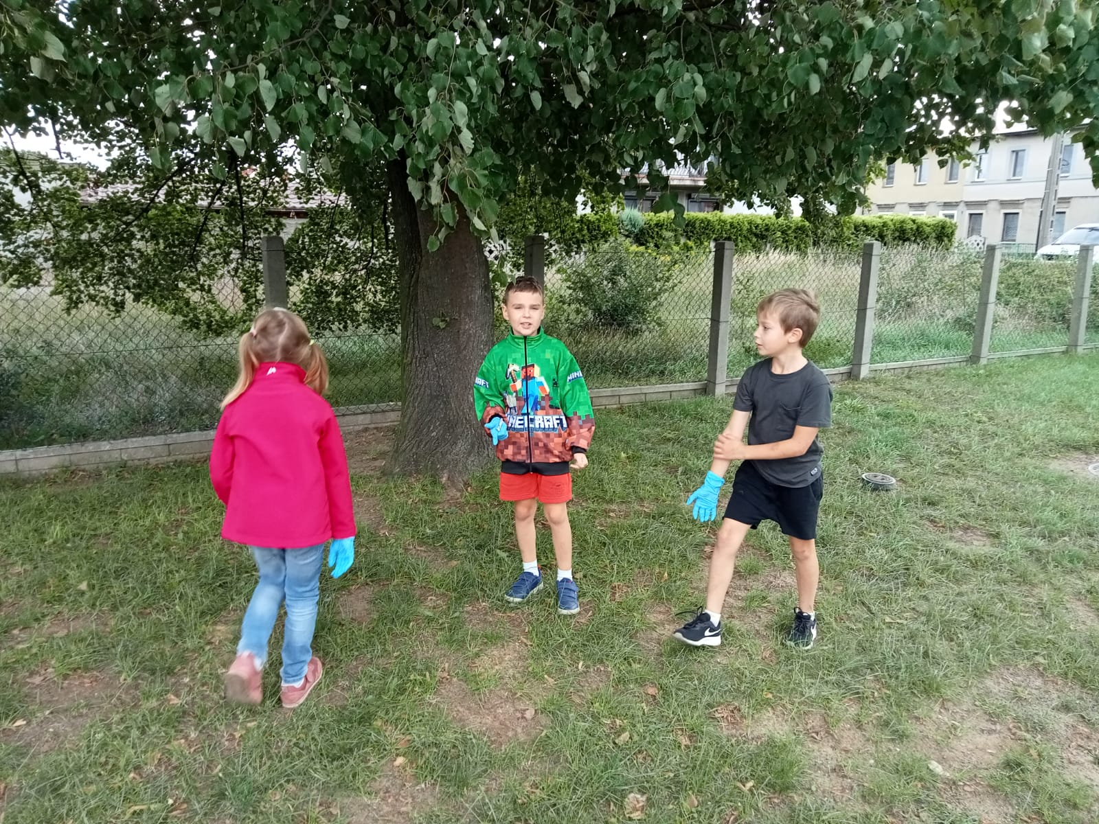 Trójka dzieci sprząta teren pod drzewem