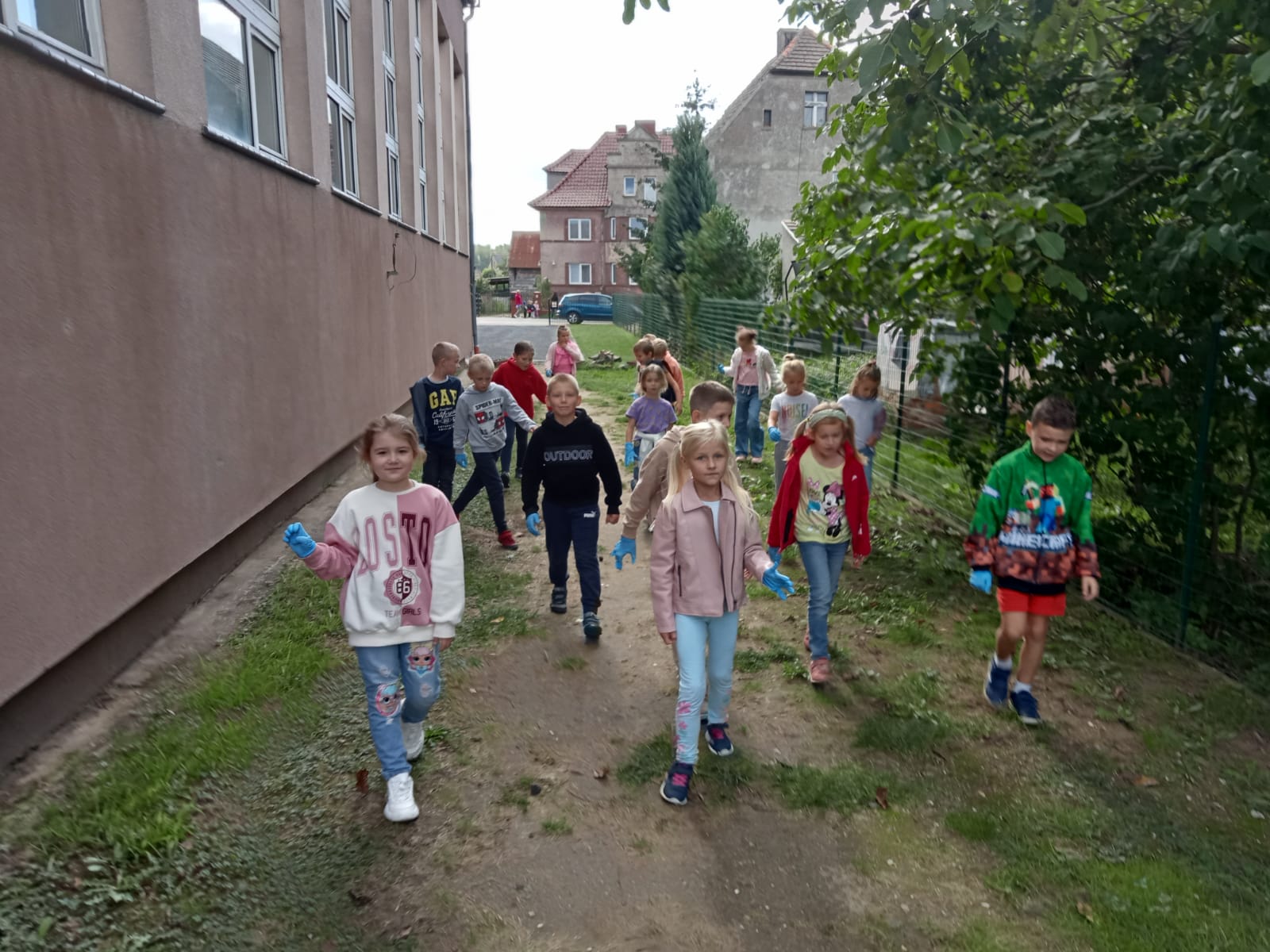 Grupa dzieci idzie wzdłuż budynku sali gimnastycznej