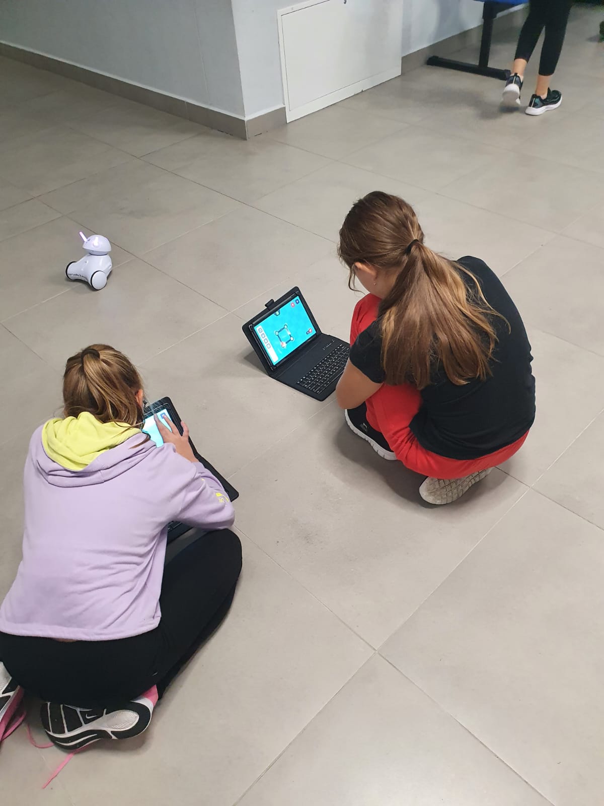 Dwie dziewczynki siedzą na podłodze i korzystają z laptopów