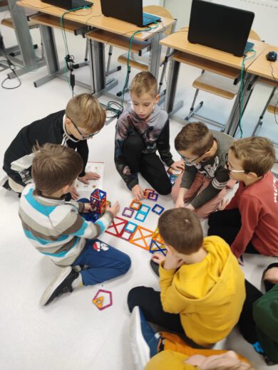 Sześciu chłopców na podłodze układa konstrukcję z klocków