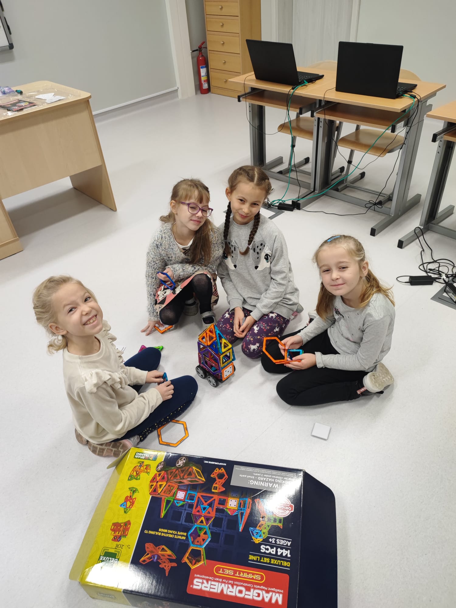 Cztery dziewczynki układają budowlę z klocków edukacyjnych