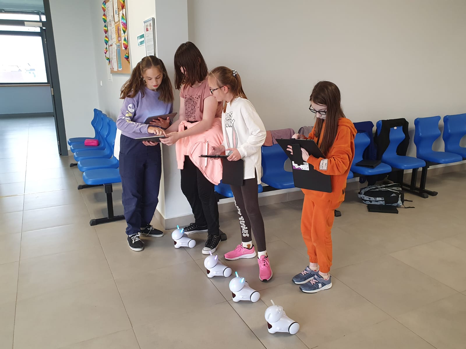 Cztery dziewczynki programują na swoich tabletach roboty