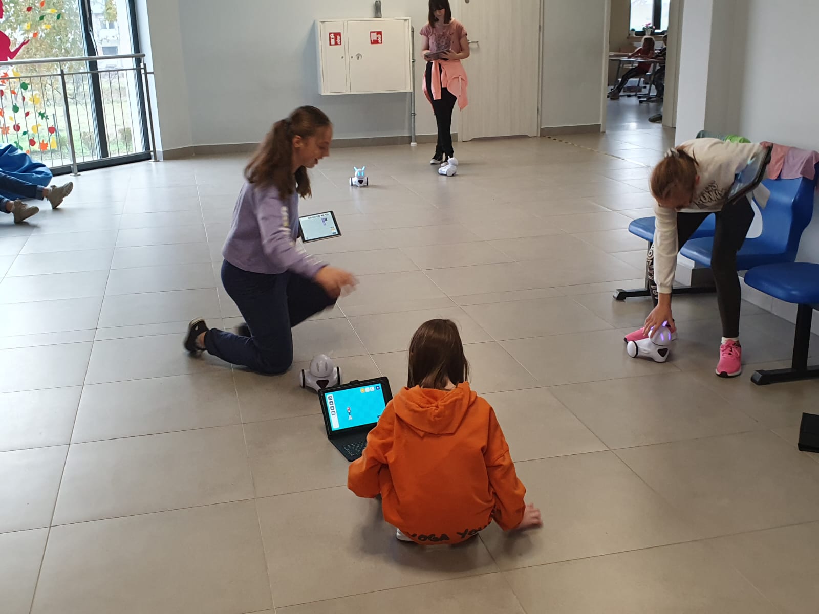Dziewczynki na korytarzu szkolnym strują swoimi robotami