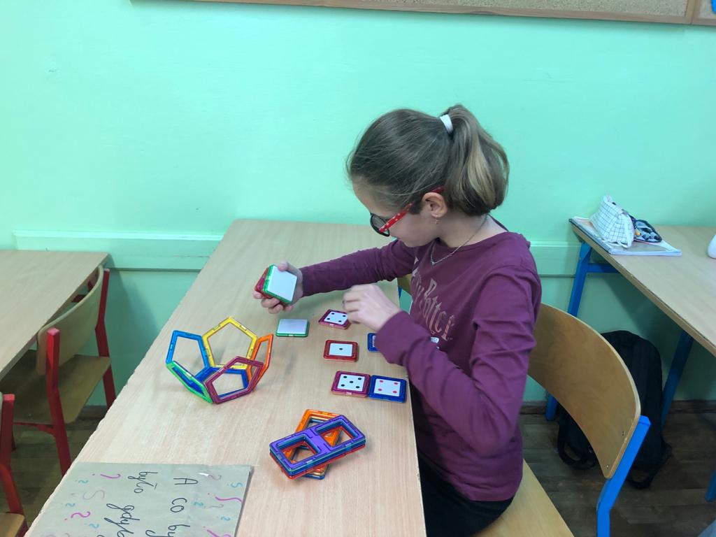 Dziewczynka układa konstrukcję z plastikowych klocków