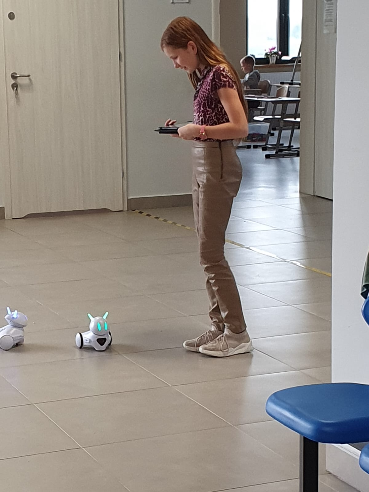 Uczennica struje swoim robotem na szkolnym korytarzu