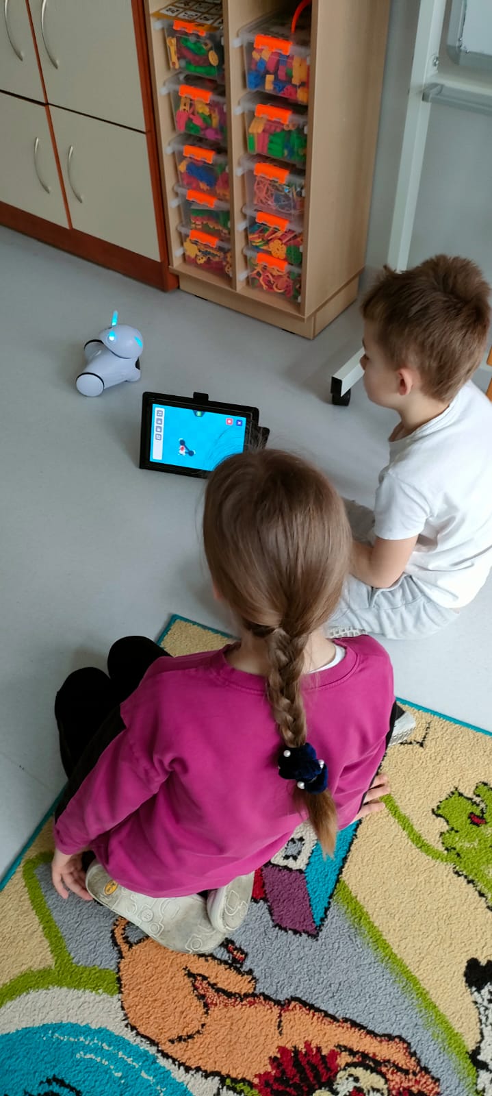 Chłopiec i dziewczynka programują robota na tablecie
