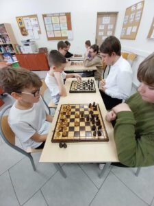 Cztery pary uczniów rozgrywają swoje partie szachowe